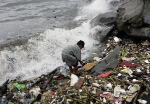 A boy salvages plastic materials washed ashore by waves in Manila bay