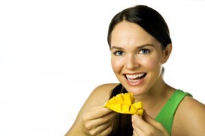 Young happy woman eating mango over white